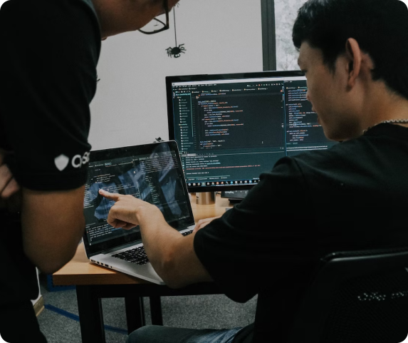 student doing coding on a computer while teacher watches